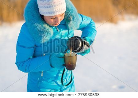 The Girl Pours Tea From A Thermos Into A Mug. Winter Photo
