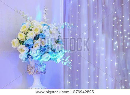 Sweet Color Roses In Vase Decorating On Wedding Party Aith White Illumination Curtain As Background.