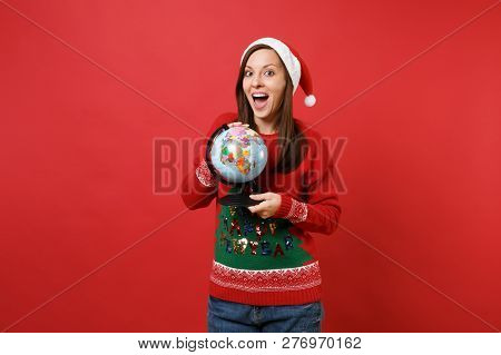 Amazed Young Santa Girl Keeping Mouth Wide Open, Looking Surprised And Holding World Globe Isolated 