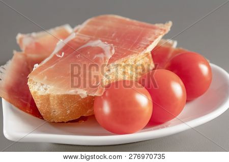 Dry Spanish Ham, Jamon, Italian Ham, Chopped Layers With Bread And Cherry Tomatoes On A White Heart-