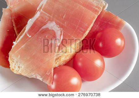 Dry Spanish Ham, Jamon, Italian Ham, Chopped Layers With Bread And Cherry Tomatoes On A White Heart-