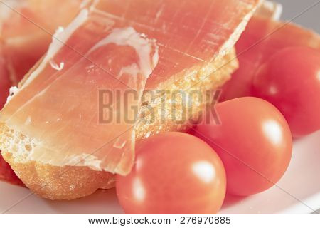Dry Spanish Ham, Jamon, Italian Ham, Chopped Layers With Bread And Cherry Tomatoes On A White Heart-