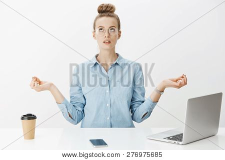 Woman Meditating In Office Sitting Near Table Having Break From Writing Article In Laptop, Drinking 