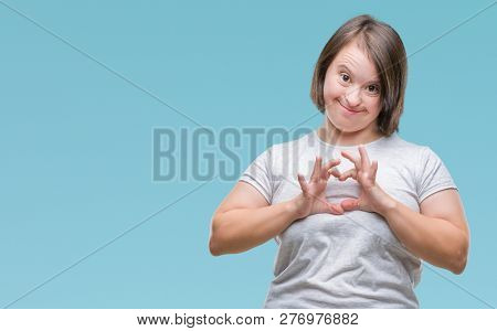 Young adult woman with down syndrome over isolated background smiling in love showing heart symbol and shape with hands. Romantic concept.