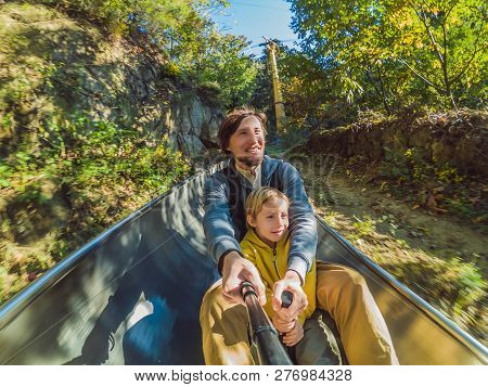 Dad And Son Have Fun On Alpine Roller Coaster