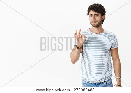 Studio Shot Of Pressured And Tired Unsure Young European Male Coworker Showing Okay Gesture While Pu