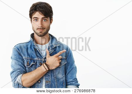 Portrait Of Attractive Hispanic Young Male With Beard And Blue Eyes Pointing At Upper Right Corner S