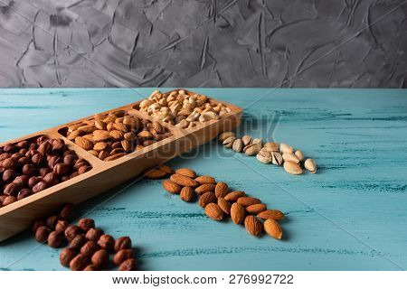 Compartmental Dish With Nuts On Blue Wooden Table. Cashew, Hazelnut, Almond.