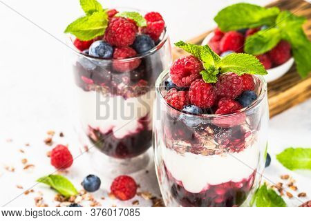 Parfait With Granola, Jam And Fresh Berries In The Glass Jar At White Table. Close Up. Healthy Desse