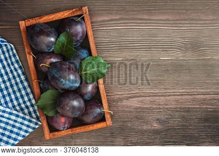 Freash Plums In Wooden Box On Wood Table Top View. Blue Pulm With Leaves. Food Fruit Background
