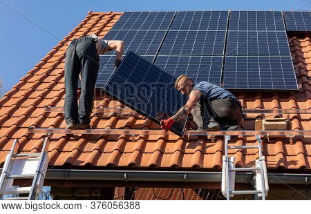 Ochojno, Poland - April 8, 2020: Workers Installing Solar Electric Panels On A House Roof In  Ochojn