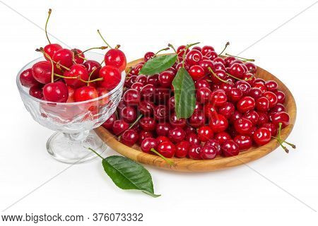 Freshly Picked Sour Cherries On The Wooden Dish And Sweet Cherries In Glass Cup, Leaves Of Cherry Tr