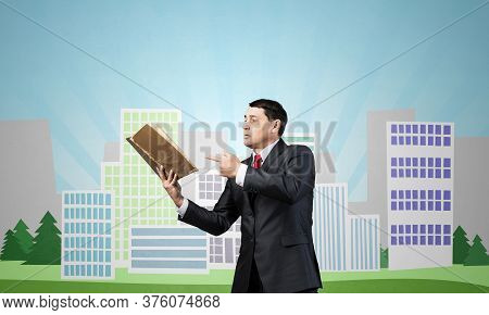 Senior Businessman Finger Pointing Into Open Book. Adult Man In Business Suit And Tie Standing On Ci