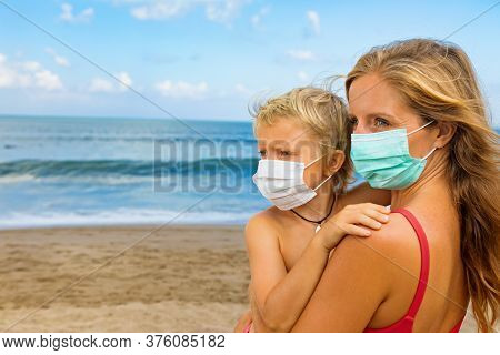 Mother Put Medical Mask On Child On Sea Beach. New Rules To Wear Cloth Face Covering At Public Place