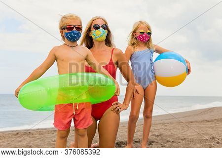 Funny Children In Sunglasses, Inflatable Toys On Tropical Sea Beach. New Rules To Wear Cloth Face Co