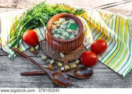 Delicious Broth With Croutons, Dill, Tomatoes On An Old Wooden Background. Lunch With Soup In A Clay
