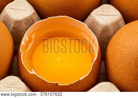 Half Broken Chicken Egg And Brown Chicken Eggs In Egg Carton On The Table. Eggs Are Loaded With Chol