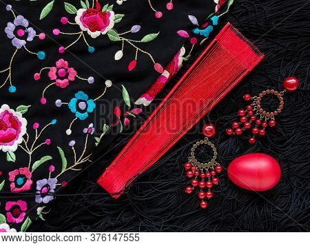 Sochi, Russia December 10, 2019: A Red Fan, Earrings And A Musical Shaker Lie On A Black Spanish Fla