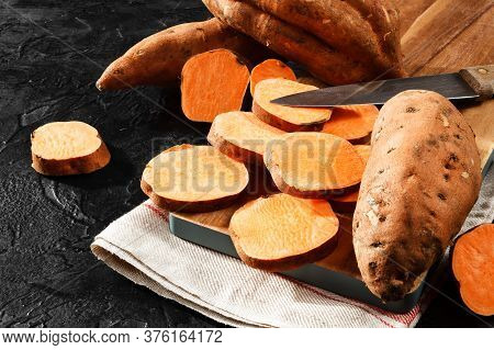 Organic Raw Sweet Potato Whole And Sliced On Wooden Kitchen Board.