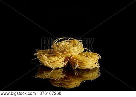 Dry, Raw Egg Pasta Capelli , Isolated On Black Background. Cooking Concept. Top View With Copy Space