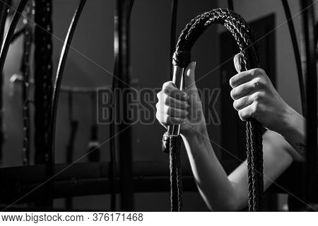 Female Hand With A Long Woven Leather Lash In A Cage. Bdsm Punishment And Pleasure. Cropped.
