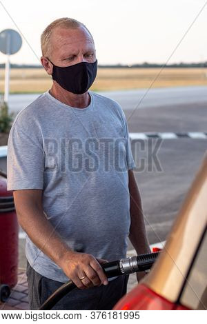 Man In A Black Protective Mask Refuel A Car At A Gas Station, Virus Protection