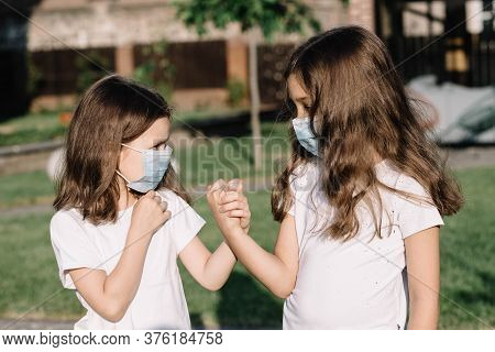 Girls In Medical Masks Hold Hand. Socialization In A Pandemic.