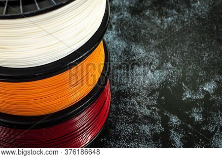 Three Coils Of Filament For 3d Printing. Bright Thermoplastic Of White, Orange And Red Colors. Reels