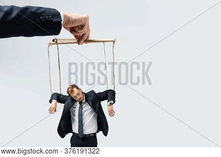 Cropped View Of Puppeteer Holding Businessman Marionette On Strings Isolated On Grey