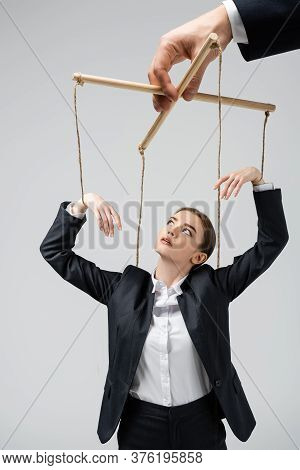 Cropped View Of Puppeteer Holding Businesswoman Marionette On Strings Isolated On Grey