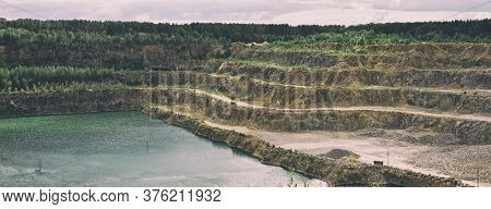 The huge open-cast quarry with lots of snones and water inside