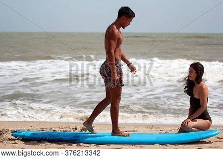 Blur Motion Of Young Handsome Man Teaching Beauty Lady For Basic Patter Of Surfing,on The Beach