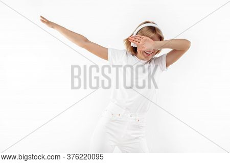 Modern Young Blonde Woman In Casual White Outfit Listening Music In Headphones Over Red Background.