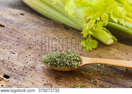 Dried Green Celery In A Wooden Spoon And Fresh Celery On A Wooden Table