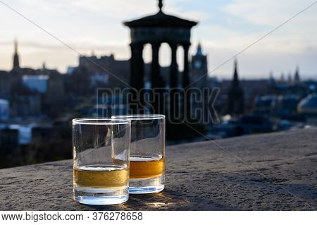 Scotch Single Malts Or Blended Whisky Spirits In Glasses With Calton Hill In Edinburgh On Background
