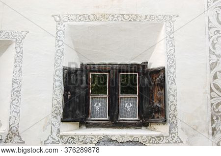 Old Wooden Window On A White Wall With Decorations In The Ancient Village Of Guarda, Scuol Municipal
