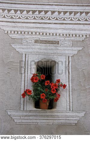 Old Small Window With Red Geraniums And Geometric Decorations On The Wall In The Ancient Village Of 