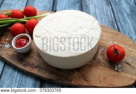 Homemade Cheese Made From Goats Milk, Small Tomatoes On A Branch, Red Sauce Lie On A Wooden Board On