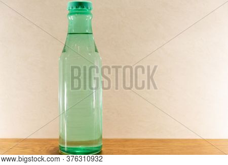 Colored Glass Bottles With Natural Water On Light And Illuminated Background