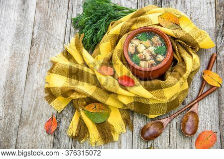 Soup With Croutons And Dill In A Clay Pot Wrapped In A Checkered Yellow Scarf For Warmth And Strewn 