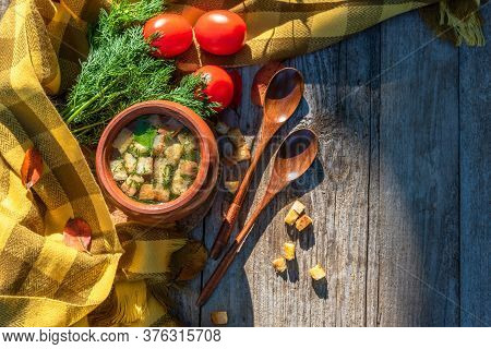 Autumn Transparent Broth With Croutons And Dill In A Clay Pot With Tomatoes Lying Next To It, A Bunc