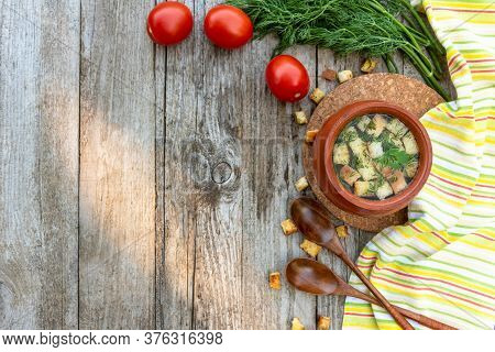 Autumn Transparent Broth With Croutons And Dill In A Clay Pot With Tomatoes Lying Next To It, A Bunc