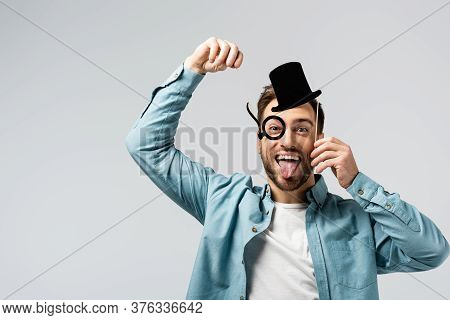 Funny Young Man With Fake Hat And Pince-nez Showing Tongue Isolated On Grey