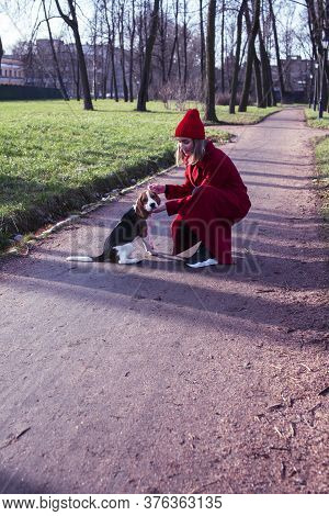Pretty Young Girl In Redd Coat Playing With Dog Outside In Green Park, Lifestyle People Concept