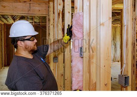 Construction Worker Installing Thermal Insulation Layer Under The Wall Using Mineral Wool With Fiber