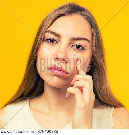 Portrait Of Sad Teen Gerl Touching Her Face And Looking For Acne On Yellow Background