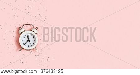 White Alarm Clock Shows About Twelve Oclock On Pink Paper Background Covered With Sequins With Copy 