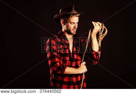Western Life. Man Unshaven Cowboy Black Background. Man Wearing Hat Hold Rope. Lasso Tool Of America
