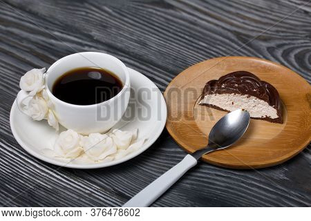 A Cup Of Black Coffee On A Saucer. Nearby Zephyr In Chocolate, Cut In Half, A Slice Is Visible. Zeph