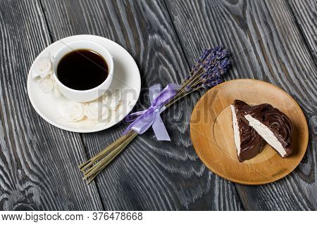 A Cup Of Black Coffee On A Saucer. Nearby Zephyr In Chocolate, Cut In Half, A Slice Is Visible. Zeph